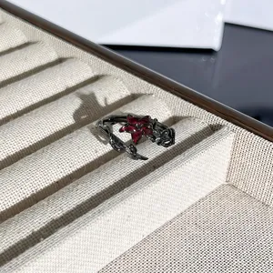Primer plano de un anillo gótico de espinas negras con una flor roja oscura central