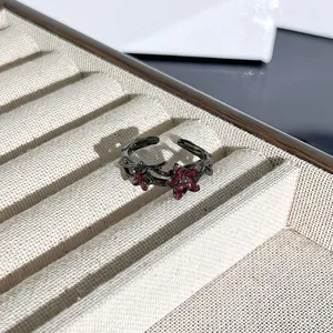 Vista de detalle macro de un anillo gótico de espinas con flores rojas en una bandeja de joyas