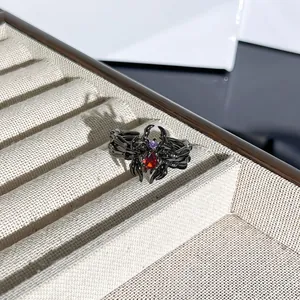 Primer plano de un anillo de araña negra gótica con una piedra roja en forma de lágrima