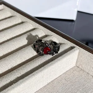 Primer plano detallado de un anillo gótico de espinas negras con piedra roja vibrante