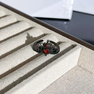 Vista macro detallada de un anillo de corona gótica negra con gema de corazón rojo