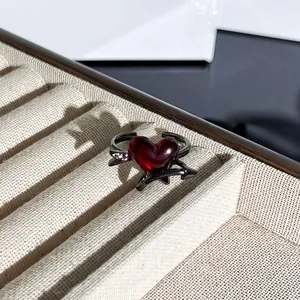 Primer plano de un anillo gótico con un corazón rojo translúcido y diseño de espinas