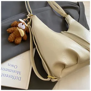 Close-up of beige leather tote bag with grainy texture and cute teddy bear charm