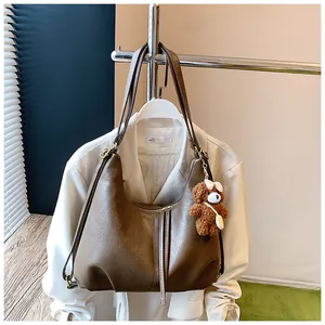 Brown large capacity vegan leather hobo bag hanging with a cute bear keychain charm detail.