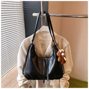 Large black faux leather tote bag with a cute bear charm hung on a professional blazer.