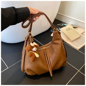 Detailed view of a large brown faux leather tote bag with a cute teddy bear charm.