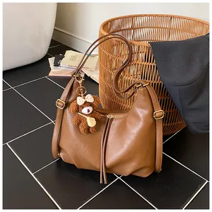 Detail shot of brown hobo bag with cute teddy bear charm and soft leather texture