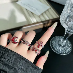 Nahaufnahme von roten Punk-Ringen mit Spinnennetz- und Kreuzmotiven im Dark-Style.