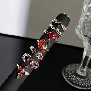 Detailaufnahme von gotischen Ringen mit rotem Emaille-Spinne- und Kreuz-Design auf einem Ständer