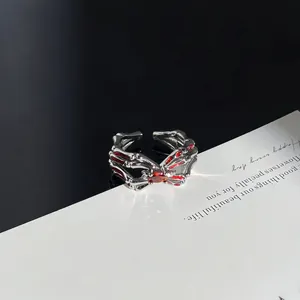 Detailansicht eines gotischen Skeletthand-Rings mit leuchtend roten Edelsteinen