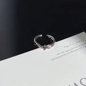 Detailaufnahme eines silbernen Punk-Rings mit dunkelrotem Spinnennetz-Muster Inlay