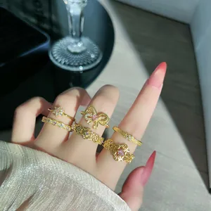 Detailaufnahme französischer Retro-Ringe, vergoldet, mit Spitzenmuster und rosa Kristallen.