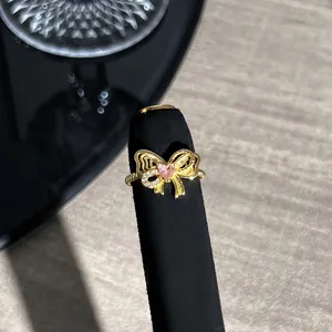 Nahaufnahme eines goldenen Vintage-Schleifenrings mit rosa Herzstein in der Mitte