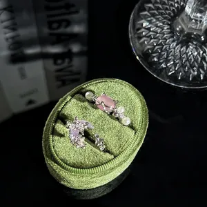 Detailansicht von lila Schmetterlings- und rosa Katzenringen in einer grünen Samtbox