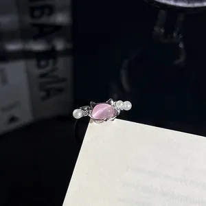 Nahaufnahme eines eleganten silbernen Rings mit rosa Katzenstein und Perlen.