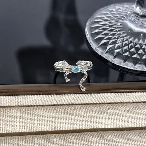 Detailansicht eines silbernen Schleifenrings mit blauem Stern und Edelsteinen.