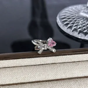 Nahaufnahme eines silbernen Schleifenrings mit funkelndem rosa Herzstein auf Display.