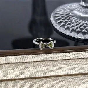 Detailansicht eines eleganten silbernen Schleifenrings mit grünen Edelsteinen und Kristallen