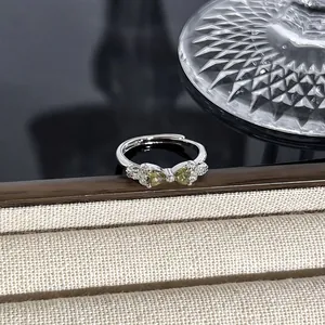 Nahaufnahme eines silbernen Schleifenrings mit funkelnden grünen Edelsteinen