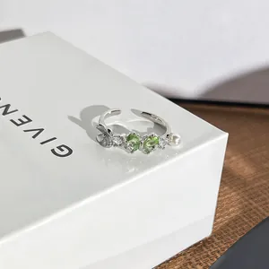 Nahaufnahme eines eleganten Silberrings mit herzförmigen grünen Edelsteinen und Perlen