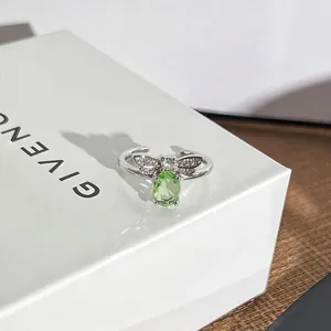 Nahaufnahme eines silbernen Bienenrings mit grünem Edelstein und funkelnden Flügeln