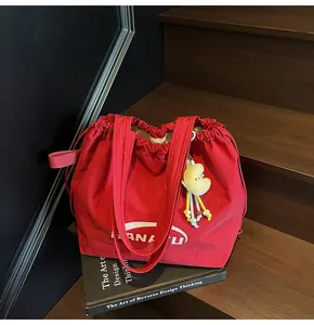 Close-up detail of large red canvas tote bag with drawstring closure on wooden steps