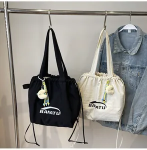 Detail of two canvas tote bags with drawstring and 'BANATU' logo hanging on rack.