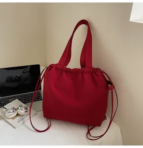 Lifestyle detail view of a large red canvas tote backpack on a white desk with props
