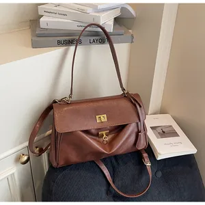 Detailed macro view of vintage brown shoulder bag showing elegant gold clasp design.