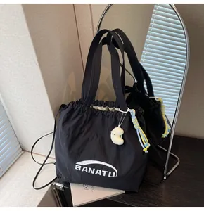 Close-up of black drawstring tote bag with white BANATU logo and cute plush charm