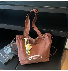 Brown nylon tote bag detail view with drawstring design and cute plush charm hangtag