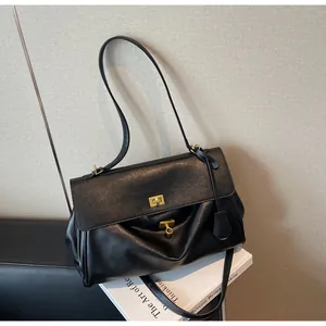 Detailed view of a black retro shoulder bag placed on books with a gold clasp.