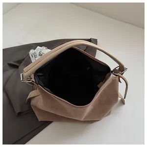 Vista detallada del interior negro de un bolso tote de ante beige con bolsillo.