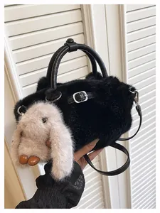 Close-up detail of the soft black faux fur handbag featuring a cute plush bunny charm