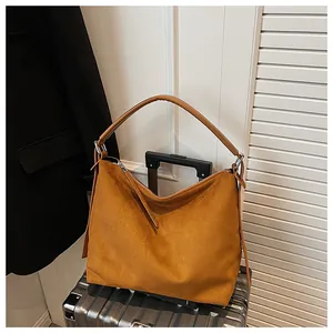Bolso hobo grande de ante mostaza sobre maleta para un estilo de viaje elegante