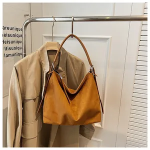 Bolso tote grande de ante marrón vintage colgado en un perchero con una gabardina