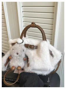 Detailed view of white faux fur tote bag featuring brown handles and rabbit charm