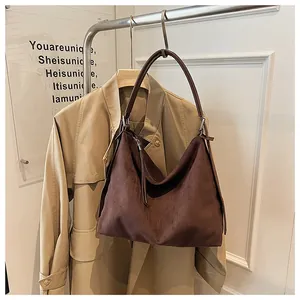 Bolso hobo de ante marrón combinado con una gabardina beige para un look chic.