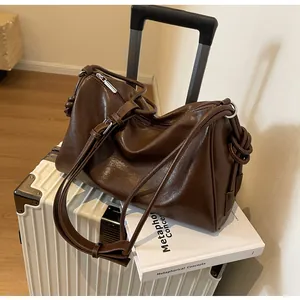 Dettaglio ravvicinato di una borsa in pelle marrone vintage su valigia bianca con libro