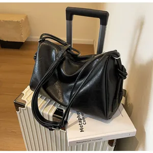 Borsa a tracolla retrò nera in pelle stropicciata di grande capacità su valigia bianca