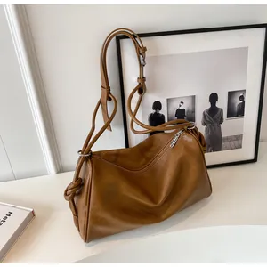 Primo piano di una borsa a tracolla vintage in pelle marrone su un tavolo bianco con arte.