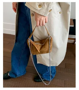 Fashionable brown suede-like chain dumpling bag held by a model in a lifestyle setting