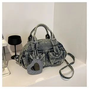 Close-up detail of a washed denim Boston bag featuring a heart-shaped glitter mirror charm