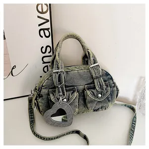 Detail view of a vintage distressed denim Boston bag featuring a stylish heart-shaped mirror charm