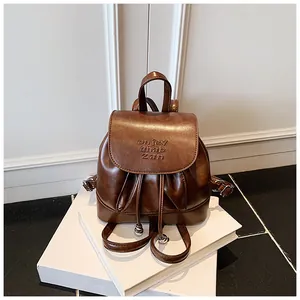 Detailansicht eines braunen Mini-Rucksacks aus weichem Leder mit Logo-Prägung auf der Klappe.