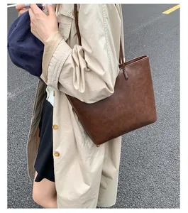 Detailed shot of a brown minimalist tote bag carried with a casual beige trench coat