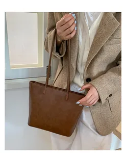 Brown faux leather tote bag held by a model in a stylish blazer