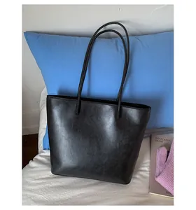 Detail shot of minimalist black large capacity tote bag with smooth leather texture