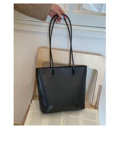 Detailed view of a black large capacity leather tote bag on a wooden chair