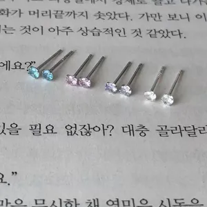 Close-up of four pairs of colorful cubic zirconia stud earrings on a book page
